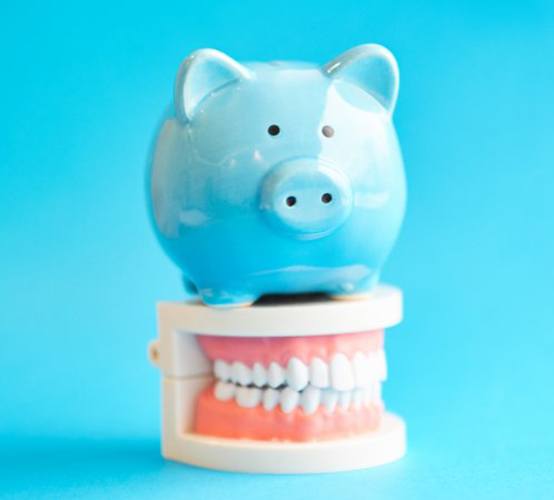 a piggy bank sitting atop a model of teeth