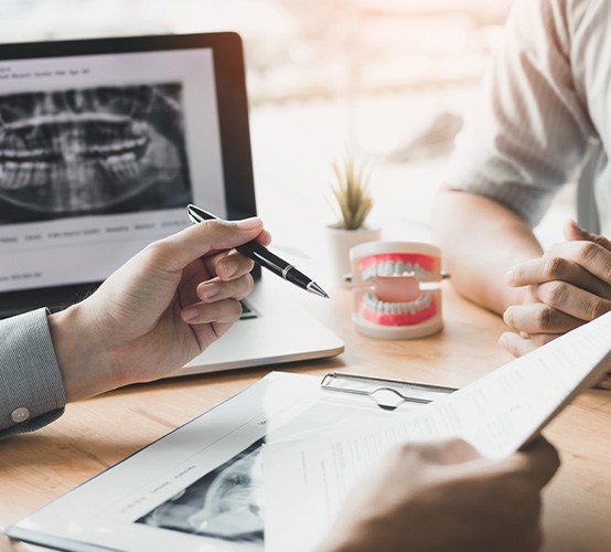 Dentist and patient discussing treatment plan and X-rays at desk