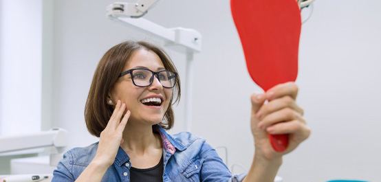 a patient checking her smile with a mirror