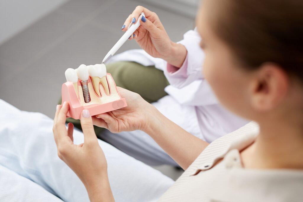 Patient holding sample dental implant as dentist points with a pen